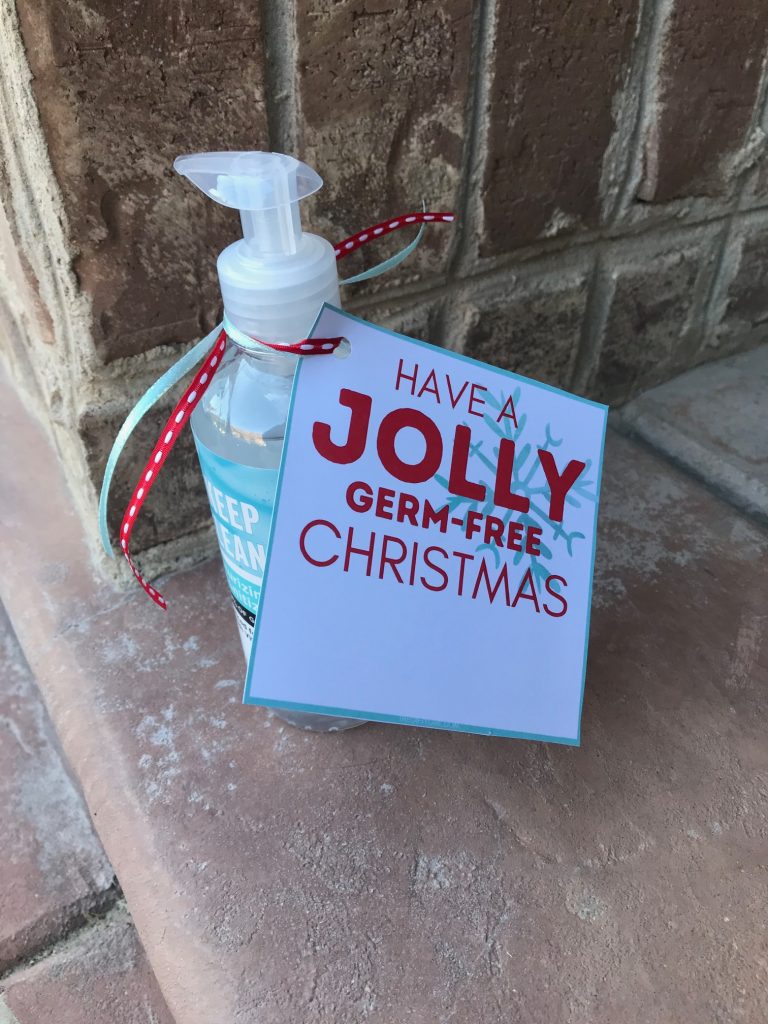Photo of a doorway with a hand sanitizer container with a gift tag that says have a jolly germ-free Christmas