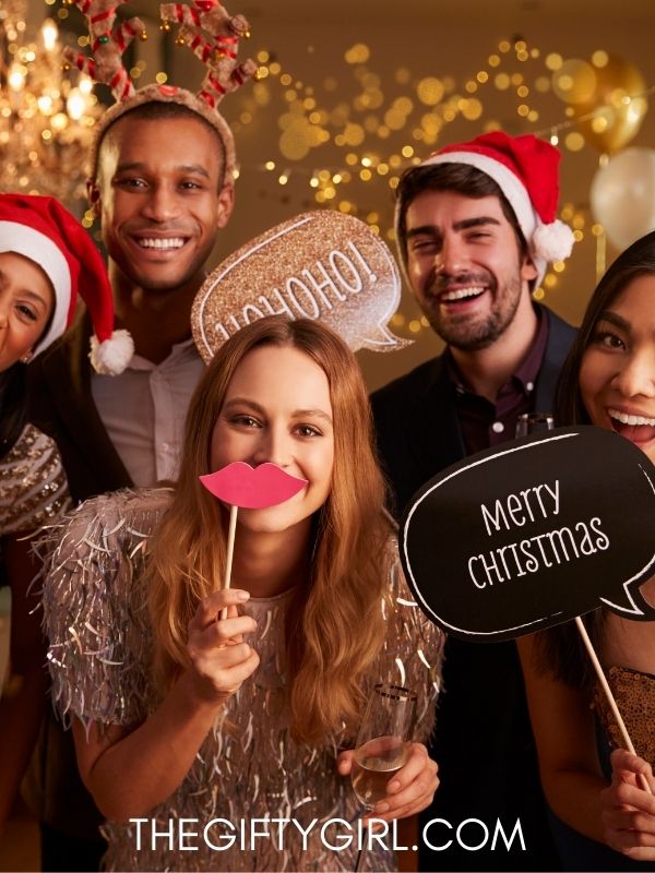 a photo of assorted adults some wearing Santa hats and holding photo props for a Christmas Photo