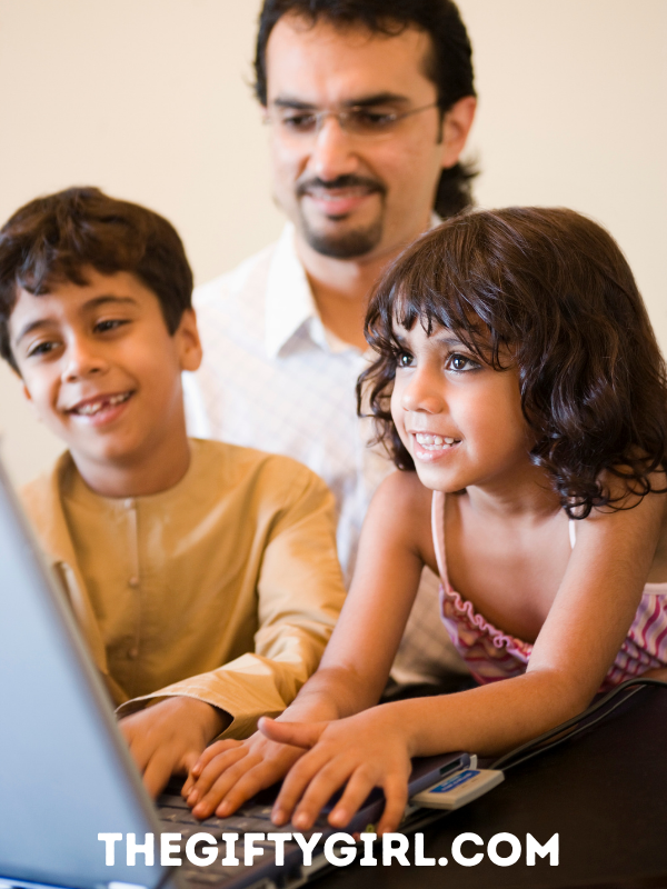A photograph of a man with two children in front of a computer.  They are smiling. Text overlay says the gifty girl dot com