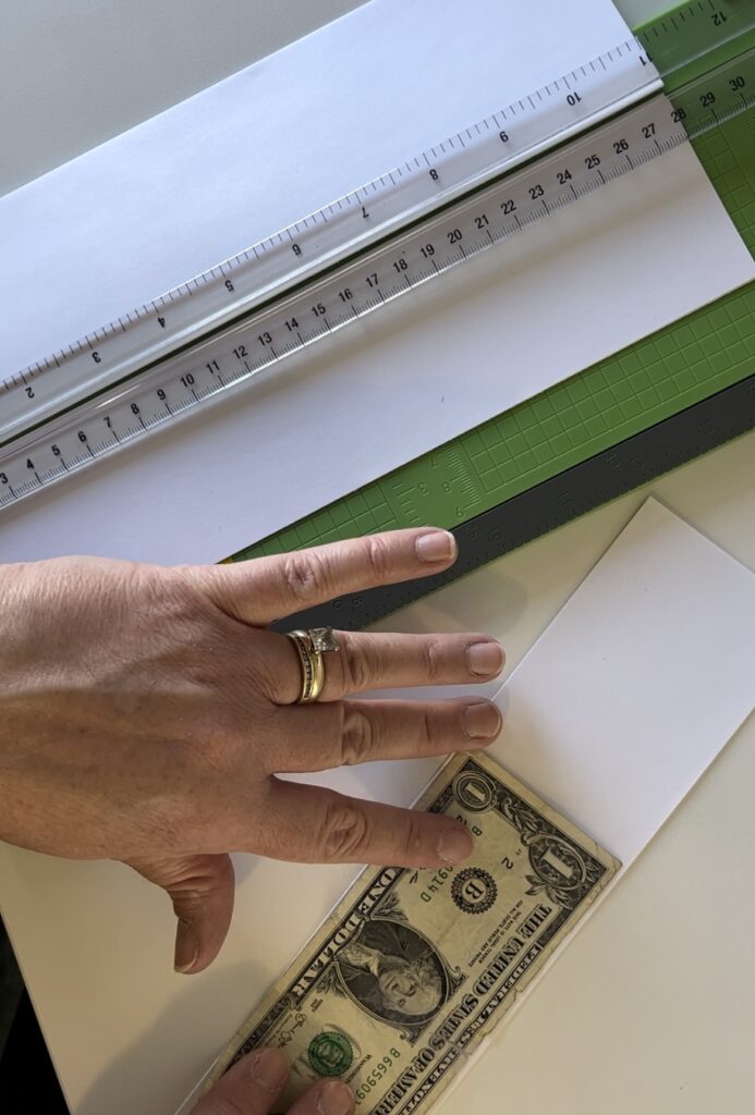 A paper cutter with strips cut the width of a dollar bill. 