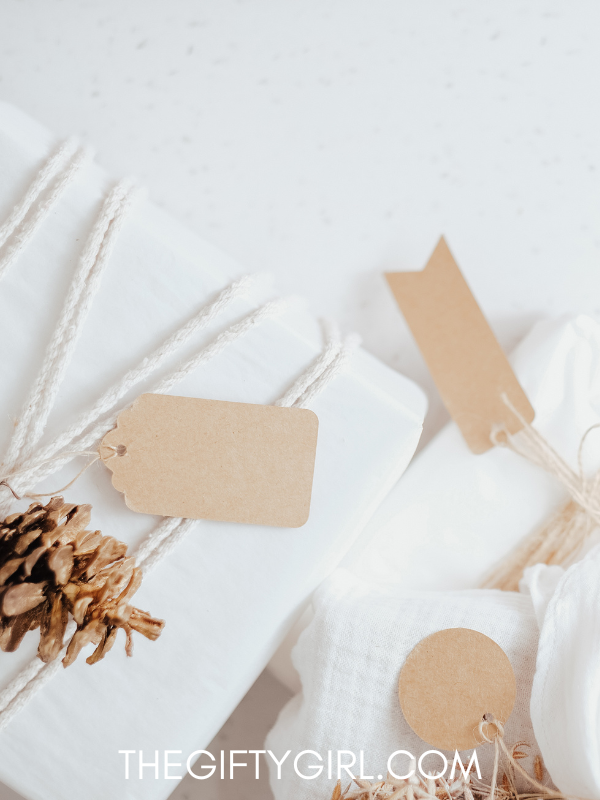 A white elephant gift box is wrapped in twine with brown paper tags and a pinecone on top.